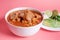 Exquisite Mexican Menudo on a white plate accompanied by a dish with condiments on the back