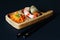 Exquisite original culinary dish of appetizing shrimp, pickled carrots and tubs of fried eggplant on beech tray on dark background