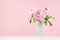 Exquisite pastel pink wedding home decor with sweet roses bouquet in modern transparent vase on soft light white wood table.