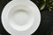 Exquisite serving white restaurant plate template on natural dark stone and leaves background