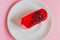 Exquisite souffle cake with lingonberry jelly, with berry glaze and coconut on a white plate, top view close-up, pink background