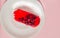 Exquisite souffle cake with lingonberry jelly, with berry glaze and coconut on a white plate, top view close-up, pink background