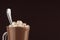 Exquisite sweet hot chocolate drink with marshmallows and silver spoon closeup, top section, detail on dark brown background.