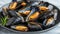 Exquisite traditional mediterranean grilled mussels served on a refined black plate