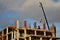 An extended boom of a truck crane lifts a concrete tank to the top floor of a building under construction.