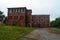 Exterior of boarded up and abandoned brick asylum hospital building with broken windows