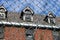 Exterior of boarded up and abandoned brick asylum hospital building with broken windows surrounded by chain link fence