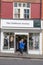 Exterior of The Childrens Society charity shop store showing sign, signage, logo and branding above entrance and window display