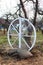 Exterior decor of wedding ceremony in a rustic style. Large wooden wheel with bags and hay next  trees in the garden. Beautiful ga