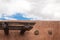 Exterior detail of red adobe building with beams, patch of blue sky with clouds