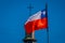 Exterior detail view of chilean flag waving with a blurred vilupulli church behind, one of world heritage wooden