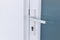 Exterior door handle and Security lock on Metal frame. Aluminum door knob. Modern white  door with metal door handle over the whit