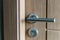 Exterior door handle and Security lock on Metal frame. Aluminum door knob. Modern wooden door with metal door handle