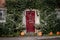 The exterior of an English countryside cottage decorated for Halloween with pumpkins on the doorstep and spiders webs or cobwebs