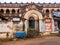 The exterior facade of an old grand mansion with weathered walls and an arched