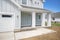 Exterior of a house with light gray board and batten siding and white column posts