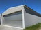 Exterior of one metal hangar for manufacturing or storage. Side view garage with closed rolling doors with concrete blocked flow.