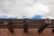 Exterior red adobe building with beams and wood sun screen slats, blue sky and clouds