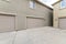 Exterior of two buildings with concrete driveway, garage doors and windows