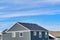 Exterior of upper floor of home with gable roof and gray horizontal wood wall