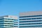 Exterior view of upper floors of two modern office building towers. Blue sky