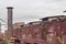 Exterior view of a warehouse district, old brick architecture, smokestack, rusting metal structures