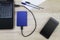 External hard drive connecting to laptop with smartphone, pens and paper on wooden desk
