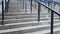 External multi-stage stone staircase. There are a lot of stairs and railings made of metal. Many steps in an urban environment,