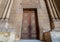 External old decorated bricks stone wall with arabesque decorated wooden door framed by stone ornate cylindrical columns