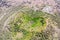 Extinct ancient crater of a volcano covered with forest near the city, aerial view