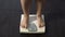 Extra body weight, female standing on scales at home to check diet result, obese