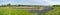 Extra large panorama over grass, natural flood are and rocks near the River Scheldt, Tielrode, Belgium