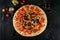 Extra large pizza with olives and tomatoes on black background