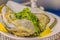 Extra large size of oysters served on ice with young lead tree leaves and a piece of lemon on the side.