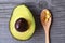 Extra virgin avocado oil capsules in a wooden spoon and fresh half organic avocado on old wooden background. Healthy eating,diet,a