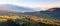 Extraordinary autumn landscape. Green fields with haystacks. Trees covered with orange and crimson leaves. Mountain landscapes.