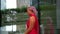 Extravagant woman is wearing red chiffon dress and walking alone in city