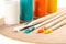 Extreme close up of art paint brushes with acrylic paint in vivid summer colors on a wooden palette