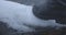 Extreme close-up of black leather boot breaking ice on river bank. Unrecognizable person strolling on snowy winter day