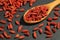 Extreme close up of dried organic goji berry fruits wolfberries in a wooden spoon on a black stone surface