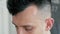 Extreme close up face of man in hairdressing salon. Barber cuts hair by clipper