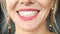 Extreme close-up female mouth with pink lipstick smiling showing white healthy beautiful teeth