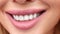 Extreme close-up female mouth with pink lipstick smiling showing white healthy beautiful teeth