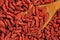 Extreme close up, flat lay of dried goji berries with wooden spoon. Macro food background texture