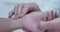 Extreme close-up on hands of doctor taking radial pulse on wrist of patient