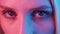 Extreme close up of human eye iris under neon light 4K. Female with beautiful makeup, glitter shadows. Womens eye
