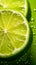 Extreme close up of a lime slices in water splashes. Sliced lime isolated on green background with water drops. Vertical