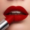 Extreme close up on model applying dark red lipstick. Makeup. Pr