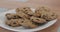 Extreme close-up of plate with biscuits standing on the table as little Caucasian child`s hand taking one cookie