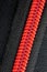 Extreme close up of a red plastic zipper and black synthetic fabric